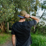 Runner wearing B-THICKET Bucket Hat outdoors, back view